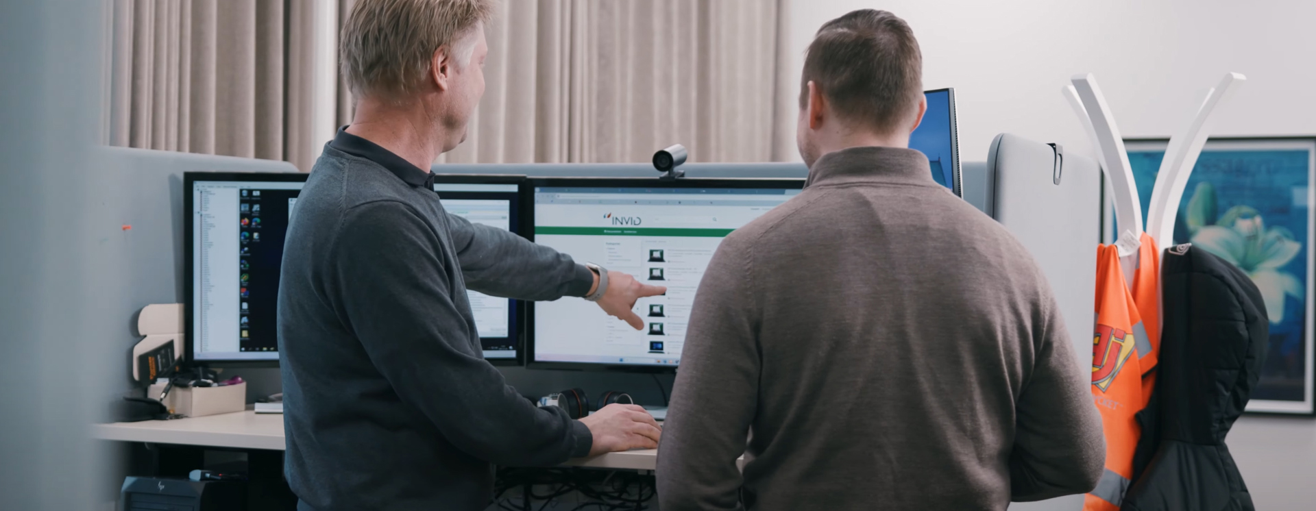 Två personer samarbetar vid flera datorskärmar och analyserar digitala lösningar i modern kontorsmiljö med fokus på affärssystem