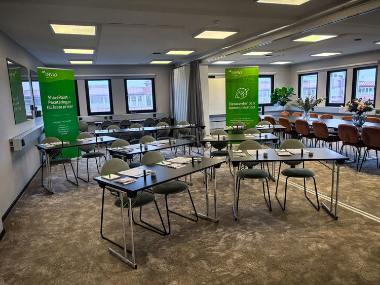 Seminarielokal i Göteborg med bord och stolar uppställda inför seminariet, med INVID-banners och blommor i rummet.