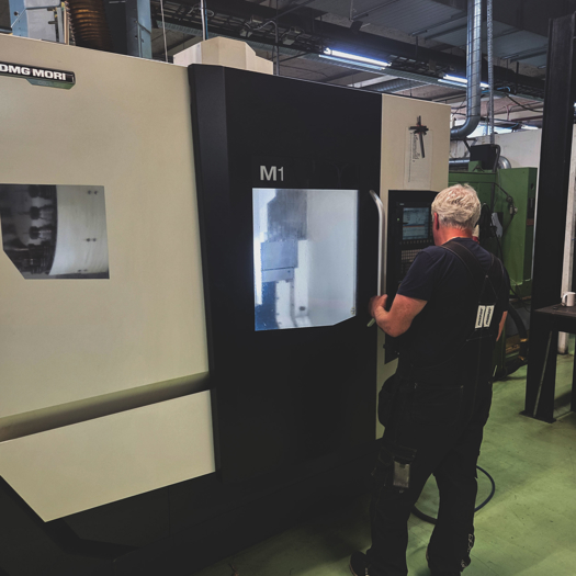 Operatör Arbetar Vid CNC Maskin I Produktionsmiljö För Bearbetning Och Tillverkning Av Metallkomponenter Med Hög