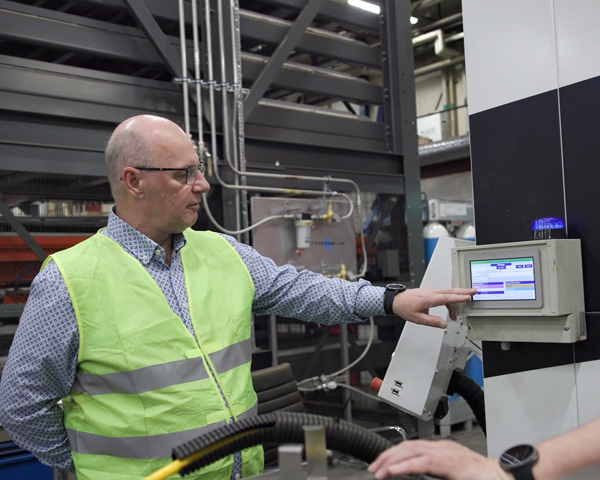 Två medarbetare i industrimiljö använder digital styrpanel och produktionssystem för övervakning, kvalitetskontroll och effektiv tillverkning