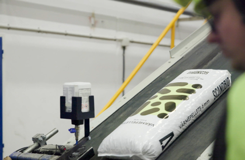Säck med Scandbio träpellets transporteras på produktionslinje i industriell miljö med fokus på hållbar bioenergi och effektiv tillverkning