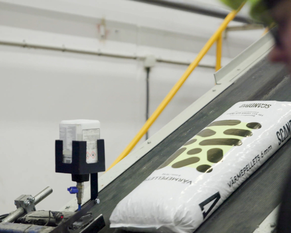 Säck med Scandbio träpellets transporteras på produktionslinje i industriell miljö med fokus på hållbar bioenergi och effektiv tillverkning