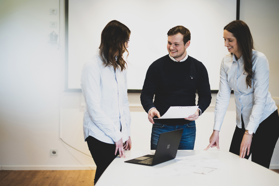 Tre medarbetare på OEM International samarbetar kring dokument och dator i konferensrum med fokus på teamwork, planering och verksamhetsutveckling