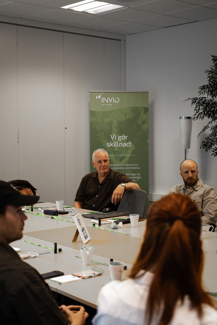 Personer sitter vid konferensbord med INVID-rollup i bakgrunden