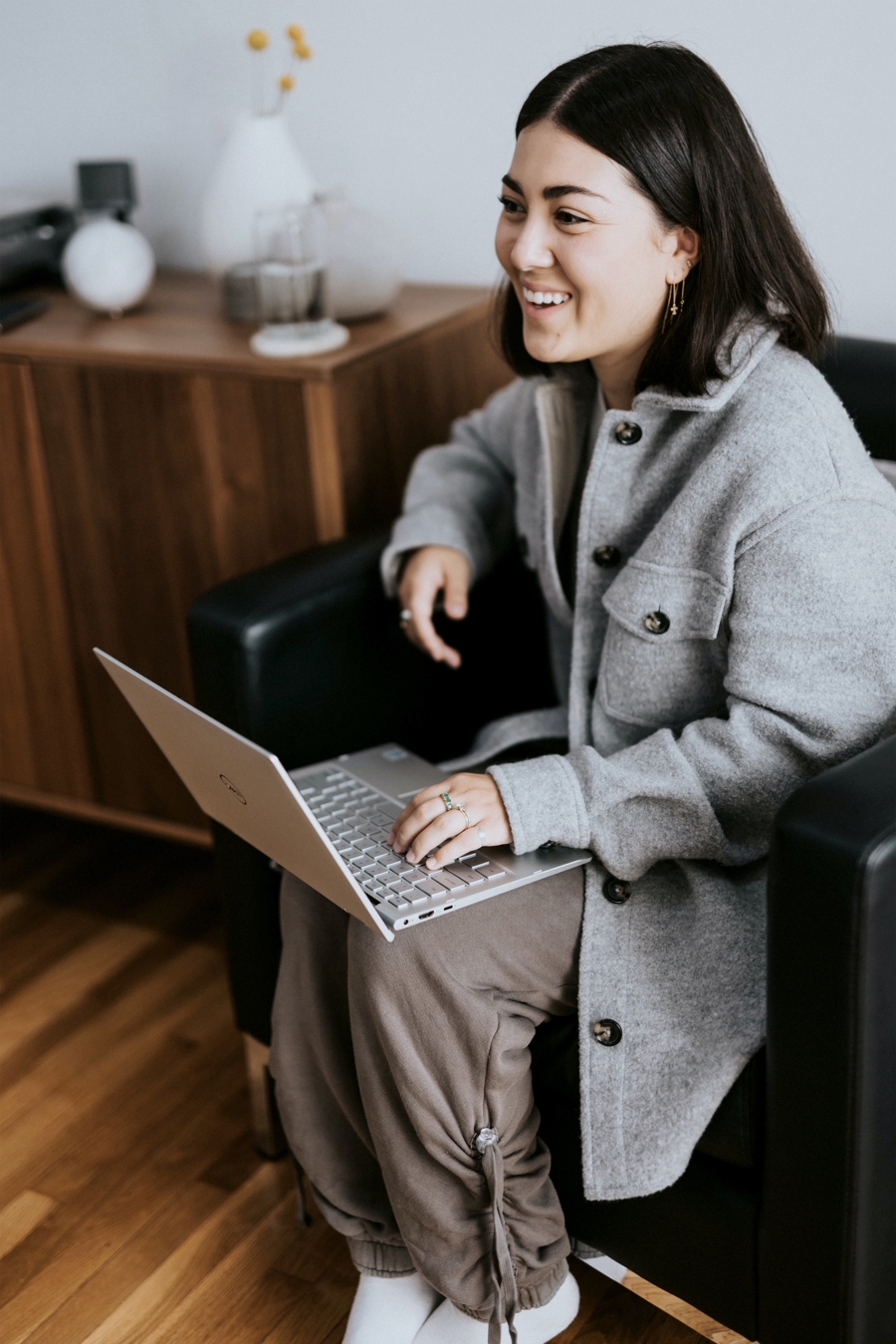 Person sitter i fåtölj och arbetar med laptop i hemmiljö eller kontorsmiljö, vilket visar flexibelt arbete, digital arbetsplats och användning av IT‑verktyg i vardagen