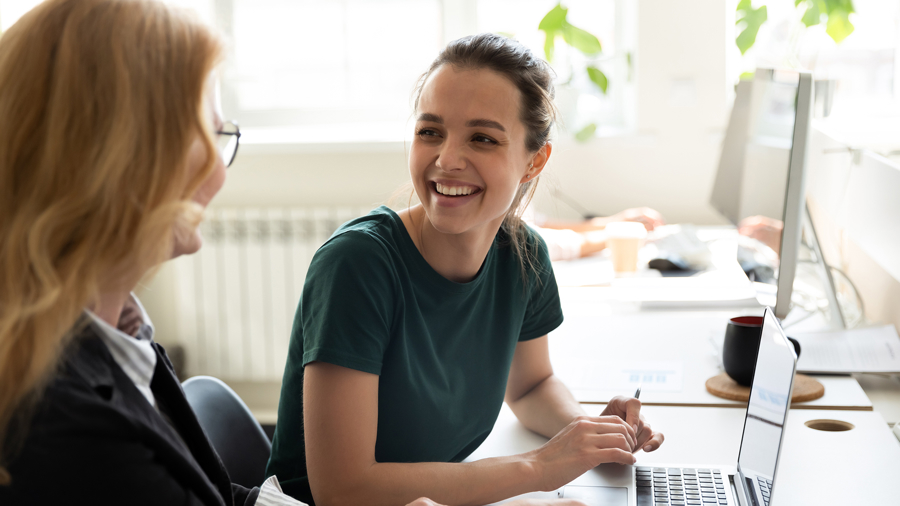 Två personer samarbetar vid laptop i modern kontorsmiljö och diskuterar digitalt arbete, analys och planering inom webb och affärssystem