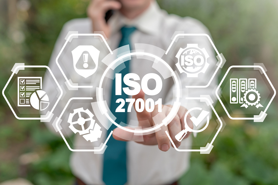 Person i skjorta pekar mot en digital symbol för ISO 27001, omgiven av ikoner för säkerhet, processer och dokumentation