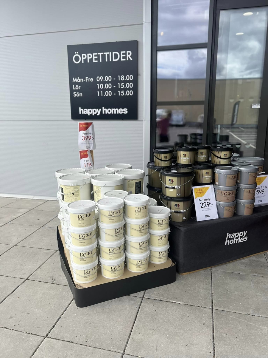 Färgburkar och målarprodukter exponerade utanför Happy Homes-butik i Linköping med öppettider och kampanjpriser vid entrén