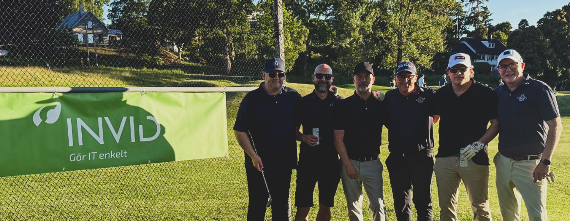 Gruppbild Från Företagsgolf Där Deltagare Poserar Framför INVID Banner På Golfbanan I Kvällssol