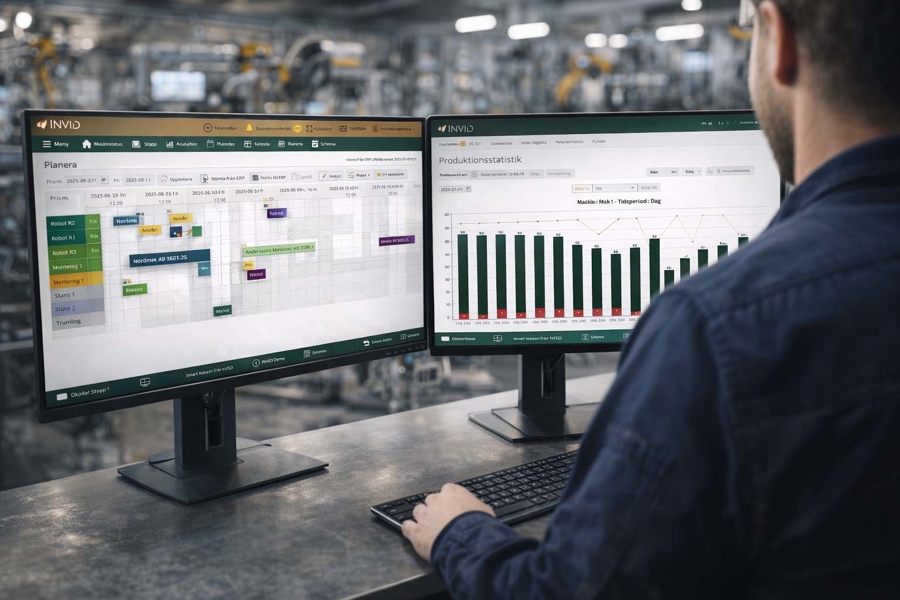 Person arbetar vid två datorskärmar i en industrimiljö, där ett planeringsverktyg och produktionsstatistik visas med scheman och diagram