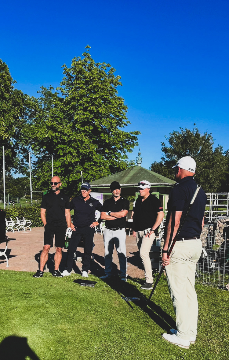 Deltagare samlas för genomgång vid företagsgolf och nätverksevent utomhus på golfklubb i strålande sommarväder