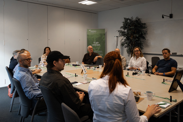 Grupp sitter runt konferensbord under nätverksmöte