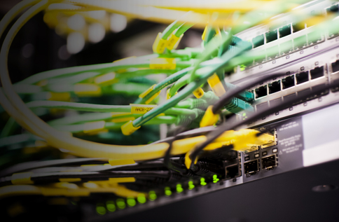 Närbild av nätverksutrustning med anslutna nätverkskablar i switch och patchpanel, vilket visar IT‑infrastruktur, datakommunikation och installation i servermiljö