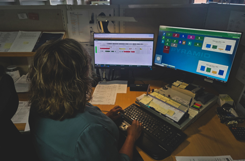 Person Arbetar Vid Flera Datorskärmar I Produktionsmiljö Och Övervakar Affärssystem, Planering Och Verksamhetspr