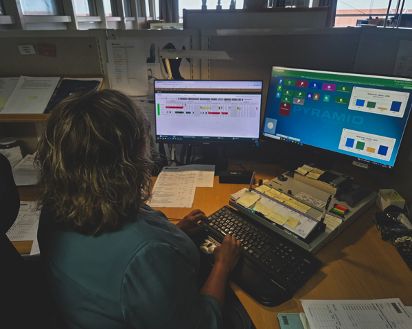 Person Arbetar Vid Flera Datorskärmar I Produktionsmiljö Och Övervakar Affärssystem, Planering Och Verksamhetspr