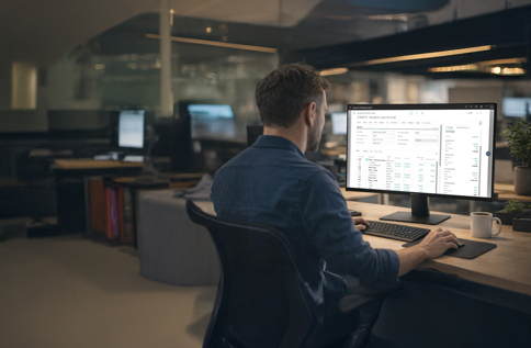 Person arbetar vid dator i modern kontorsmiljö och använder Microsoft Dynamics 365 Business Central för att hantera affärsprocesser, kunddata och ekonomi i digitalt affärssystem