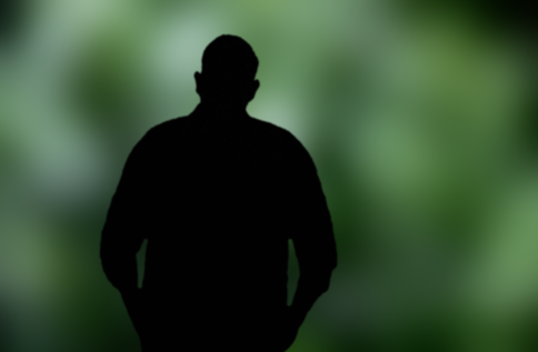 Siluett av en person mot grön bakgrund, där konturen av överkropp och händer i fickor framträder tydligt